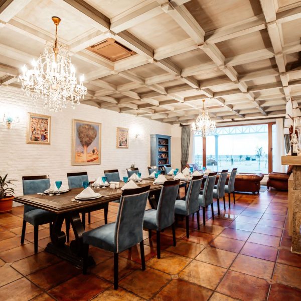restaurant private room with table for 12 blue chairs white brick walls wide window and paintings